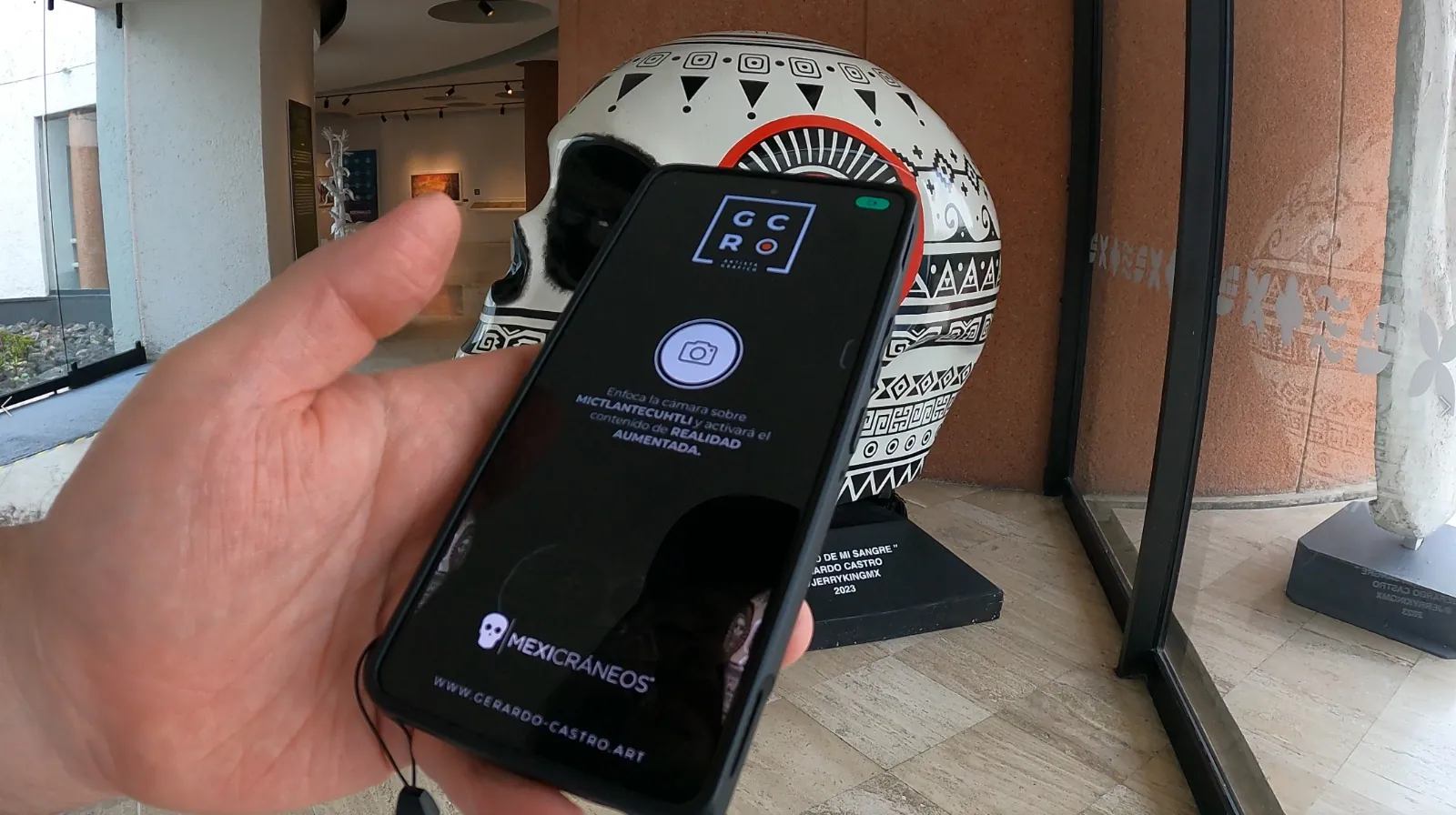 Visitante sosteniendo un celular con la app abierta frente al cráneo